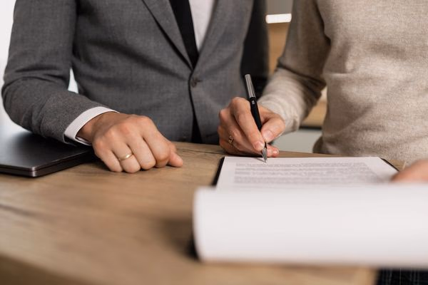 A person carefully reviewing and signing a legal contract at a professional desk