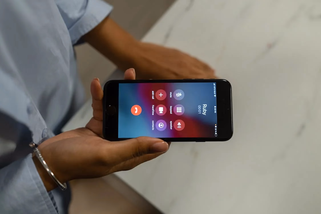 Close-up of a person holding a smartphone displaying an active call screen, urgently contacting a lawyer