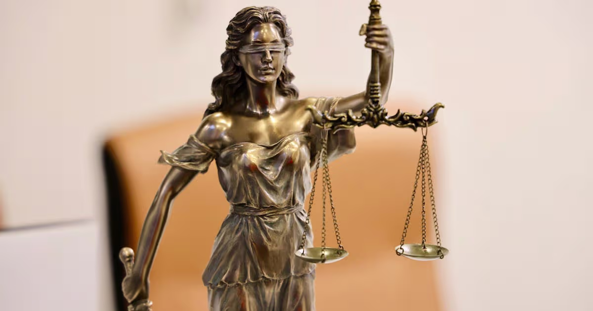 Lady Justice statue holding scales against a plain background