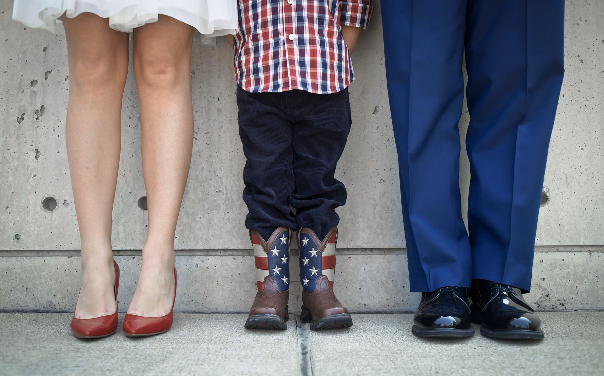 Two parents standing on either side of a young child outdoors