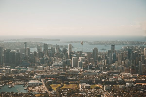 Aerial view of Sydney, Australia's urban skyline and harbour coastline on a clear, sunny day